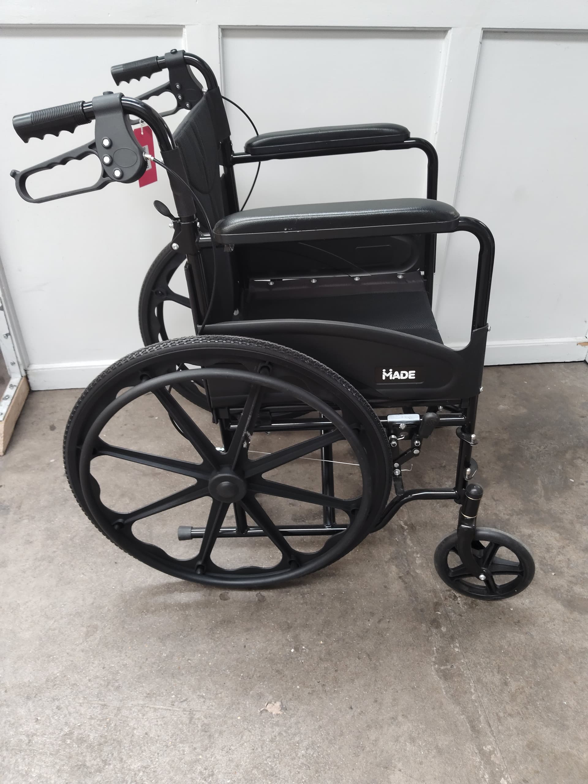 A Made self propel wheelchair in black (small tear to arm rest).